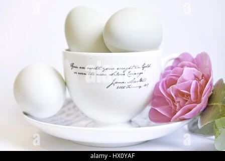 Festivals, religieux, Pâques, Studio shot of œufs sur tasse et soucoupe en céramique avec fleur de camélia rose. Banque D'Images