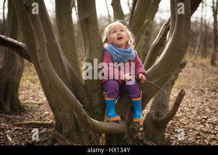 Cute girl s'amusant sur l'arbre dans la forêt. Banque D'Images