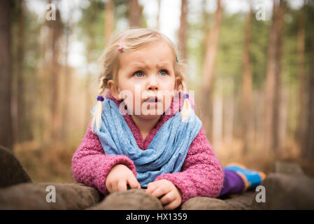 Peu girle observer la nature dans la forêt tout en se trouvant sur les troncs des arbres Banque D'Images