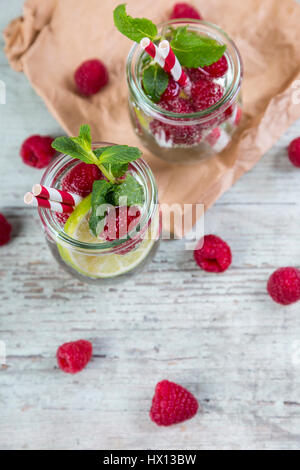 Verres d'eau avec limes et detox rasperries décoré de feuilles de menthe Banque D'Images