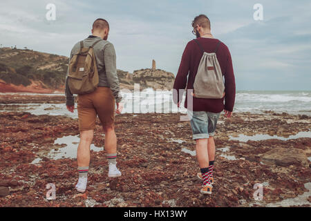 L'Espagne, Oropesa del Mar, deux jeunes hommes marchant sur Stony Beach Banque D'Images