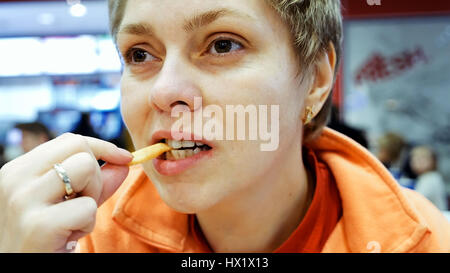 Jeune femme mange fast food à café restaurant Banque D'Images