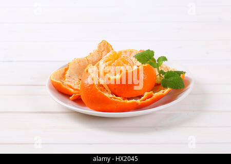 Peeled tangerine disposés en peels on white plate Banque D'Images