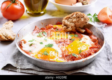 Oeufs au plat avec les tomates et le bacon dans une poêle à frire Banque D'Images