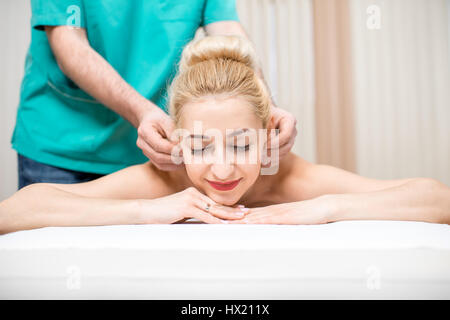 Woman getting massage oreille allongé sur le canapé dans la salle de massage Banque D'Images