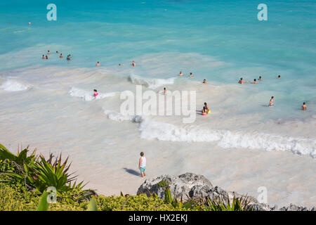 Vue de dessus de la mer des Caraïbes sous ciel bleu avec des nageurs sur la plage de Tulum, péninsule du Yucatan, au Mexique, le vert des plantes tropicales palmiers foregroun Banque D'Images