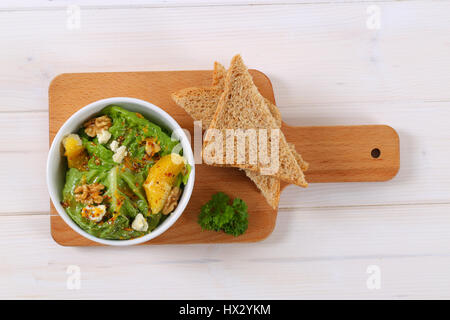 Bol de salade de chou chinois à l'orange, noix, fromage et pain grillé Banque D'Images