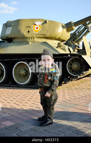 Bébé garçon en uniforme militaire sur fond de réservoir. Le 9 mai, la seconde guerre mondiale, defender, le 23 février. Banque D'Images