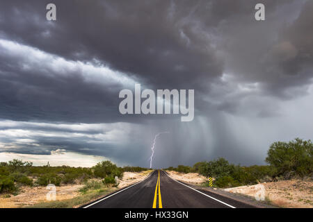 Des nuages de tempête spectaculaires avec éclair frappent au bout d'une route vide dans le désert de l'Arizona Banque D'Images