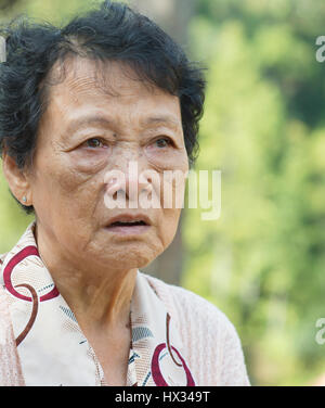 Portrait de femme adulte senior asiatique inquiète au jardin extérieur parc dans la matinée. Banque D'Images