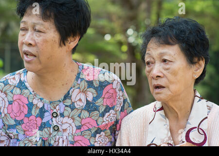 Candid shot of Asian femmes âgées chatting at outdoor park le matin. Banque D'Images