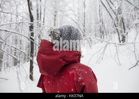 Une dame dans une veste rouge les raquettes dans la forêt après une tempête de neige dans la région de Hastings Highlands, Ontario, Canada. Banque D'Images