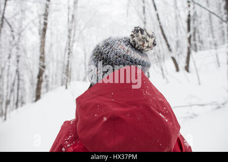 Une dame dans une veste rouge les raquettes dans la forêt après une tempête de neige dans la région de Hastings Highlands, Ontario, Canada. Banque D'Images