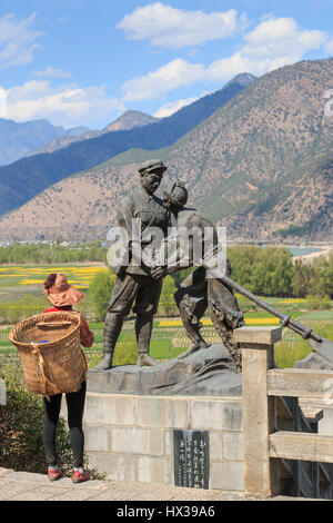 ShiGu, Chine - le 17 mars 2017 : femme NaXi en face d'une statue célébrant l'Armée Rouge de Chine dans le village de ShiGu près de Lijiang Banque D'Images