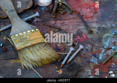 Désordre désordre avec de vieux pinceau et peinture sur bois avec vis enduisit bits de couleurs à l'huile. Bien usé, abandonné les outils de peinture. Banque D'Images