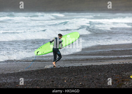 Homme avec green surf sur la plage de Famara Lanzarote Banque D'Images