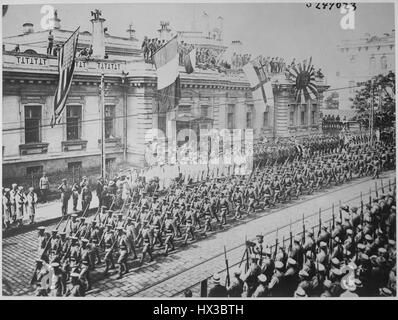 Des foules de badauds regarder depuis le trottoir comme des rangées de soldats et marins de plusieurs pays marcher en formation lors d'un défilé à l'extérieur du bâtiment du Siège, alliés de Vladivostok, en Russie, en 1918. L'image de courtoisie des Archives nationales. Banque D'Images