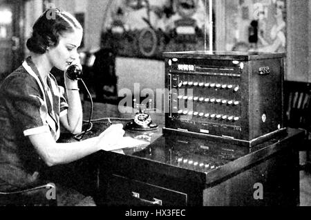Une femme standardiste parle dans un casque pendant qu'un petit téléphone branch exchange standard, 1950. Banque D'Images