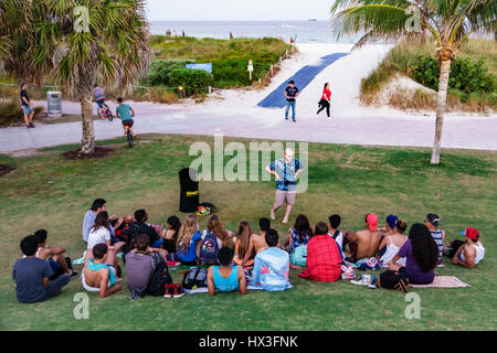 Miami Beach Florida, South Pointe Park, parc public, adultes homme hommes, femme femme femme dame, assis sur l'herbe, pelouse, jeunes adultes, bible St Banque D'Images