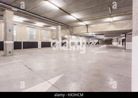 Parc souterrain d'un centre commercial avec des colonnes et des conduits de ventilation Banque D'Images