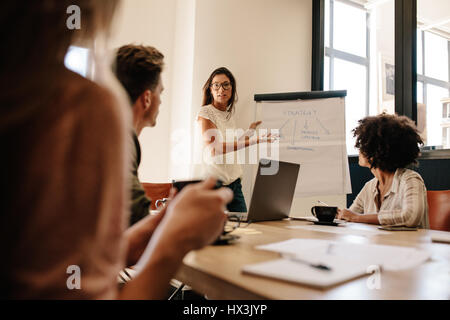 La femelle l'explication nouvelle stratégie d'affaires à des collègues dans la salle de conférence. Bureau d'affaires réunion de l'équipe en salle du conseil. Banque D'Images