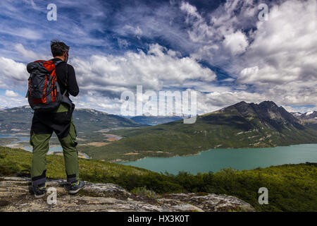 Sac à dos avec l'homme debout sur la falaise, dans la montagne au-dessus du lac Banque D'Images