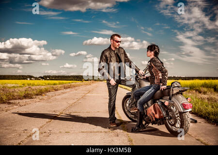 Biker homme et jeune fille se tient sur la route et regarde dans la distance Banque D'Images