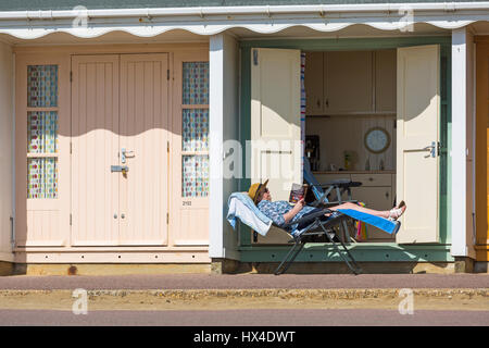 Bournemouth, Dorset, UK. Mar 25, 2017. Météo France : belle chaude journée ensoleillée comme visiteurs chef de la mer à profiter du soleil sur les plages de Bournemouth. Woman relaxing on sunlonger au beach hut lecture James Patterson livre 14e crédit de péché mortel : Carolyn Jenkins/Alamy Live News Banque D'Images