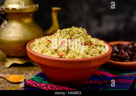 Libre d'un bol en terre cuite avec taboulé, une salade arabe levantin typique, sur un set de table pour le déjeuner ou le dîner, avec un verre d'or dans le background Banque D'Images