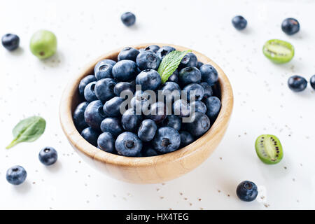 Bleuets frais dans bol en bois sur fond blanc Banque D'Images