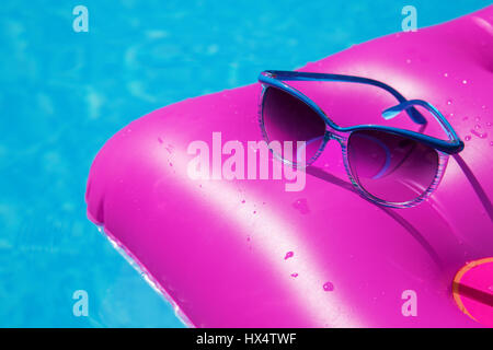 Lunettes de soleil avec matelas rose à la piscine - maison de vacances concept tropical Banque D'Images