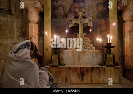 Un chrétien orthodoxe éthiopien prie à la chapelle arménienne de la division du Raimante ou les robes à l'intérieur de l'église du Saint-Sépulcre dans la vieille ville chrétienne Jérusalem-est Israël Banque D'Images