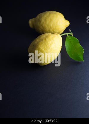 Citron jaune frais avec feuille verte isolée sur fond noir Banque D'Images