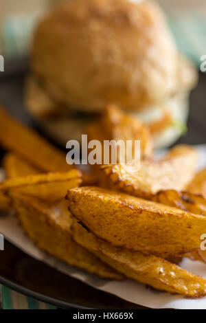 Profondeur de champ photo du burger et frites coupées à la main sur une plaque. Banque D'Images