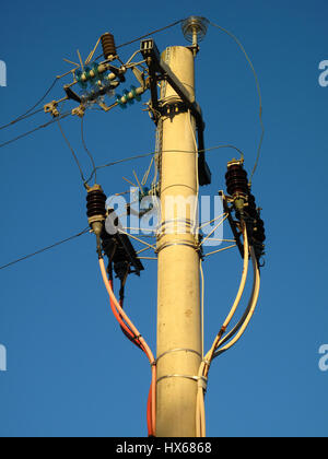 Un vieux poteau de wit fils connectés sur un fond de ciel bleu Banque D'Images