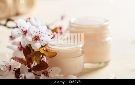 Crème hydratante et cerisiers en fleurs sur fond de bois Banque D'Images