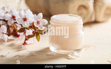 Crème hydratante et cerisiers en fleurs sur fond de bois Banque D'Images