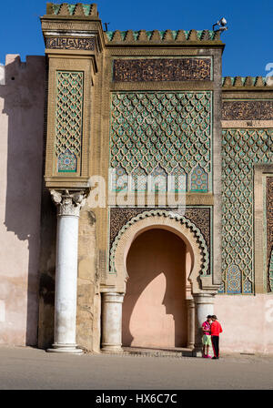 Meknes, Maroc. Deux jeunes hommes se tenant debout en face de la porte Bab Mansour, construit 1672-1732. Banque D'Images