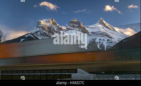 Vue floue transparente en mouvement à grande vitesse voies ferrées du train de marchandises du canadien Pacifique. Canmore Bow Valley Landscape Three Sisters Mountain Peak Skyline Banque D'Images