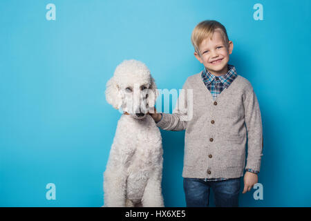 Garçon au chien à la mode. L'amitié. Animaux domestiques. Studio portrait sur fond bleu Banque D'Images