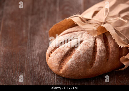 Miche de pain de seigle en sac de papier sur la table en bois. Arrière-plan de boulangerie Banque D'Images