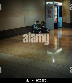 Deux étudiants de manger de pique-niquer sur le sol à côté d'un photo-me istant Photo Booth dans un centre commercial de Cambridge Banque D'Images