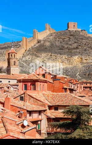 Maisons et rues d'Albarracin contre la pente de la colline avec des murs de la ville sur le dessus sur une journée ensoleillée sous un ciel bleu. Teruel, Espagne. Banque D'Images