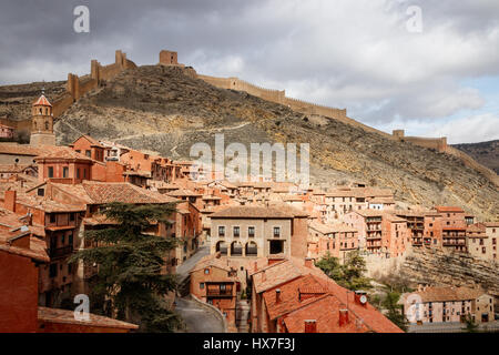 Belle vue sur la ville médiévale Albarracin dans la lumière du soleil, avec des collines et les remparts de la ville à l'arrière-plan sous un ciel nuageux. Teruel, Espagne. Banque D'Images