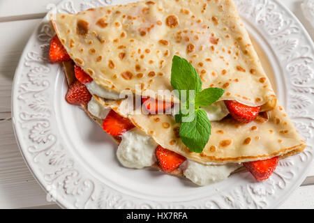 Crêpes à la crème et fraises à l'ancienne table en bois Banque D'Images