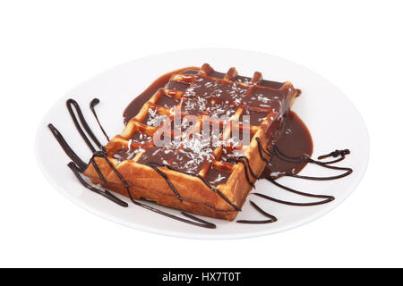 Une gaufre belge, versé le chocolat fondu et saupoudrés de noix de coco se trouvant sur la plaque, isolé sur fond blanc. Banque D'Images