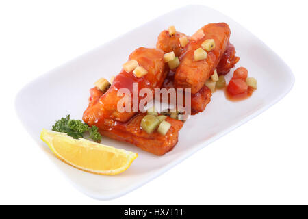 Les spécialités chinoises, aigre-doux panés et frits sauce les lanières de porc, sur plaque blanche avec des tranches d'ananas isolé sur fond blanc Banque D'Images