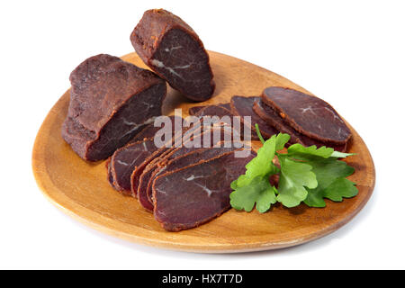 Basturma, filet de boeuf séché, viande émincée, sur une assiette en bois, isolé sur fond blanc. Banque D'Images