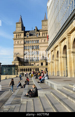 Les passagers du train se baigner dans le soleil de l'après-midi sur les marches de la gare de Lime Street, Liverpool, alors qu'ils attendent leurs trains d'arriver. Banque D'Images