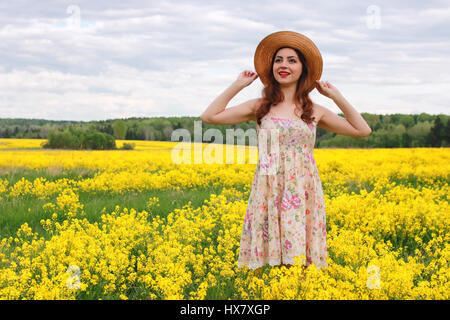 Jeune fille dans un champ de fleurs avec panier et un chapeau Banque D'Images